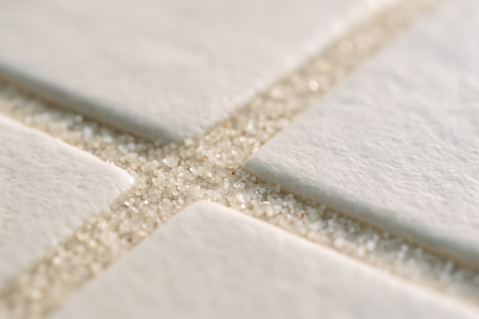 Close-up of fine Gulf sand and salt residue embedded in tile grout lines inside a Clearwater Florida beach home